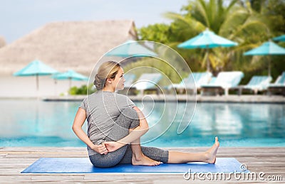 Woman making yoga in twist pose on mat Stock Photo