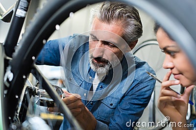 Woman and man as bike mechanics in workshop reparing Stock Photo