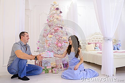 Woman and man hand Christmas presents its half in spacious bedro Stock Photo