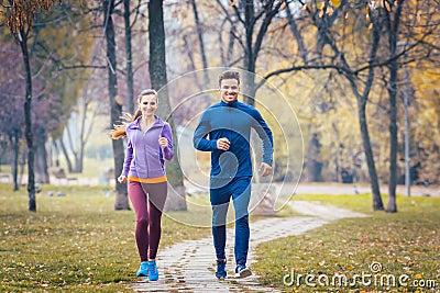 Woman and man running in autumn park for sport Stock Photo