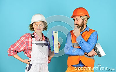 Woman and man safety hard hat. Discussing renovation with contractor. Sign contract with workers. Price list. Couple Stock Photo