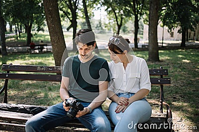 Woman and man sitting on bench and looking at camera display Stock Photo