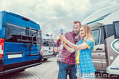 Woman and man taking selfie in front of RV or camper in anticipation Stock Photo