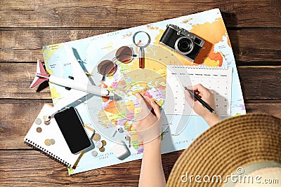 Woman marking calendar at table with world map. Travel during summer vacation Stock Photo