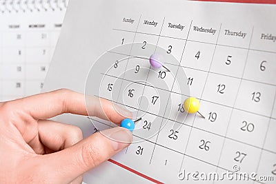 Woman marking date in calendar with drawing pin Stock Photo