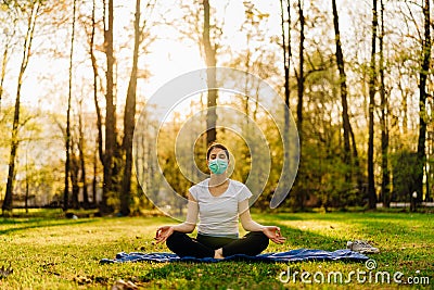 Woman with mask meditating in nature alone.Social distancing and active healthy lifestyle. Mindfulness meditation practice. Stock Photo