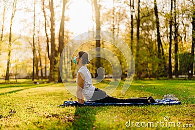 Woman with mask meditating/practicing yoga in nature alone.Social distancing and active healthy lifestyle. Mindfulness meditation. Stock Photo