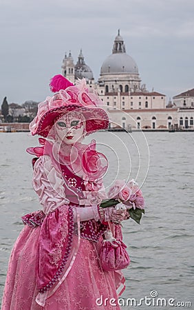 Woman in mask and ornate pink costume with the Salute Church in background during Venice Carnival Editorial Stock Photo