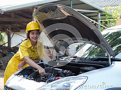 The woman in the mechanic& x27;s work set is using a wrench to open the parts of the engine Stock Photo