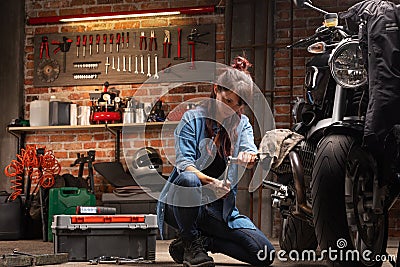 Woman mechanic working on a vintage motorbike Stock Photo