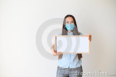 Woman in a medical mask stands with a blank board Stock Photo