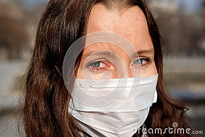 A woman in a medical mask walks alone on the street during the quarantine. Portrait of a female in a protective face mask against Stock Photo