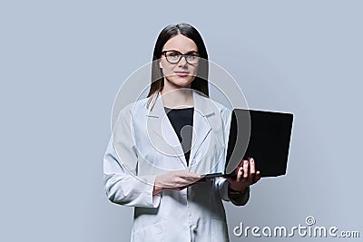 Woman medical scientist, pharmacist in white coat using laptop on grey background Stock Photo