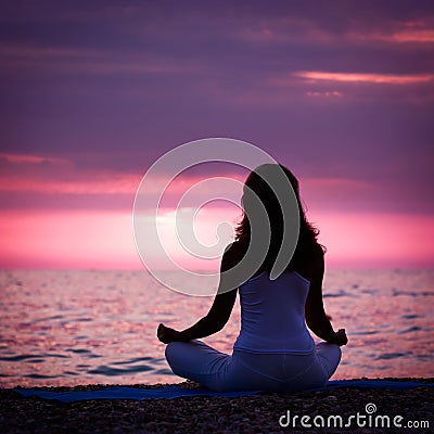Woman Meditating in Lotus Position by the Sea Stock Photo