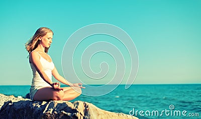 Woman meditating in lotus yoga on beach Stock Photo