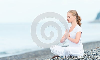 Woman meditating in lotus yoga on beach Stock Photo