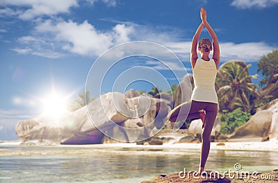 Woman meditating in yoga tree pose over beach Stock Photo