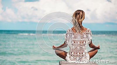 Woman meditation in a yoga pose at the beach Stock Photo