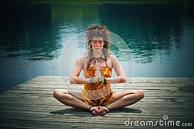 Woman in a meditative yoga position by the lake Stock Photo