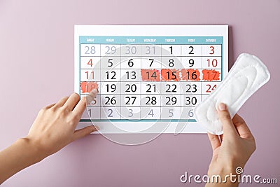 Woman with menstrual pad and calendar on color background Stock Photo