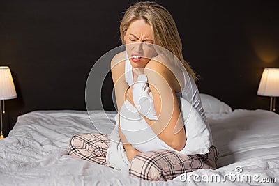 Woman in menstrual pain sitting in her bed Stock Photo