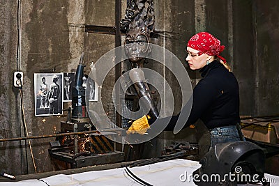 Woman metal artist at work in workshop using metalcut saw Editorial Stock Photo