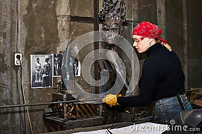 Woman metal artist at work in workshop using metalcut saw Editorial Stock Photo
