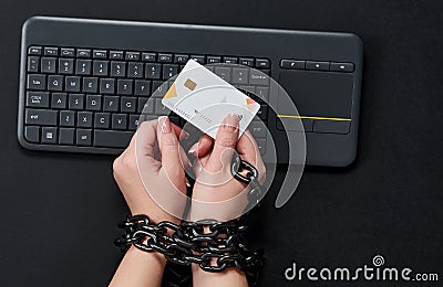 Woman with metal chain holding credit card over keyboard, online shopping addiction concept Stock Photo