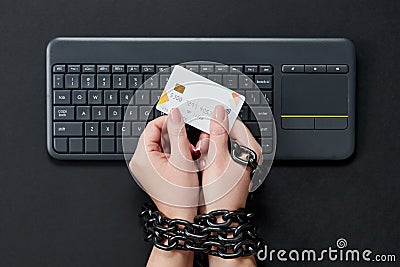 Woman with metal chain holding credit card over keyboard, online shopping addiction concept Stock Photo