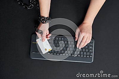 Woman with metal chain holding credit card over keyboard, online shopping addiction concept Stock Photo