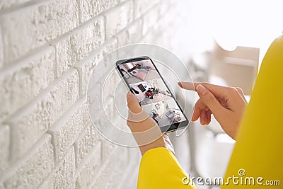 Woman monitoring modern cctv cameras on smartphone indoors. Home security system Stock Photo