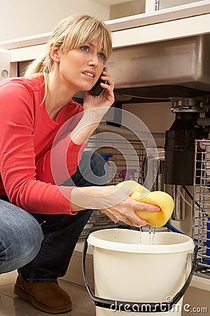 Woman Mopping Up Leaking Sink Stock Photo