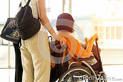 Woman with mother in wheelchair waiting for boarding at International airport. Editorial Stock Photo