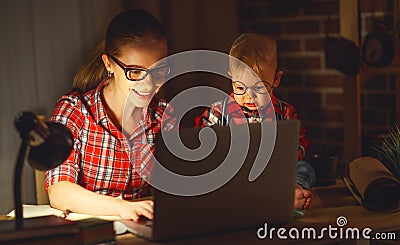 Woman mother working with a baby at home behind a computer Stock Photo