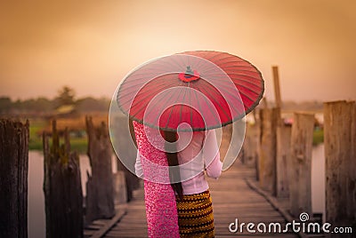 Woman Myanmar holding traditional red umbrella on U Bein wooden Stock Photo