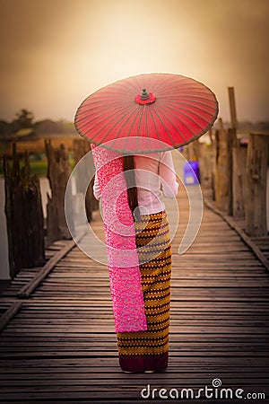 Woman Myanmar holding traditional red umbrella on U Bein wooden Stock Photo
