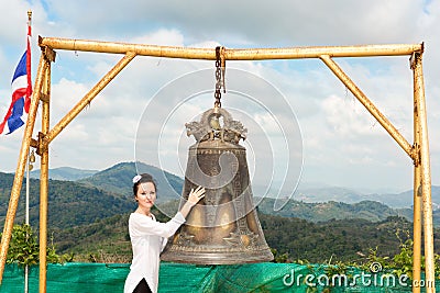 Woman near Thai gong in Phuket. Tradition asian bell in Buddhism temple in Thailand. Famous Big bell wish near Gold Buddha Stock Photo