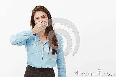 Woman needs keep mouth shut. Portrait of casual european female brunette in blue blouse, covering mouth with palm and Stock Photo