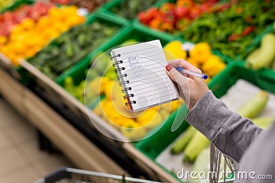 Woman with notebook in grocery store, closeup. Shopping list on paper. Stock Photo