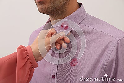 Woman noticed lipstick kiss marks on her husband`s shirt against white background, closeup Stock Photo