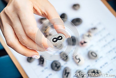 Woman numerologist hand with pebble stone with Infinity symbol Stock Photo