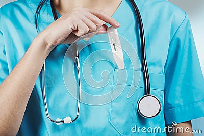 Woman nurse or doctor close up while she is putting a thermometer inside her chest pocket Stock Photo