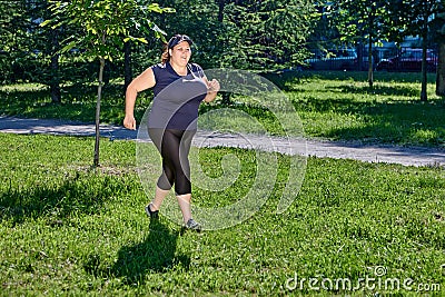 Woman with obesity jogging in public park on a sunny summer day. Stock Photo