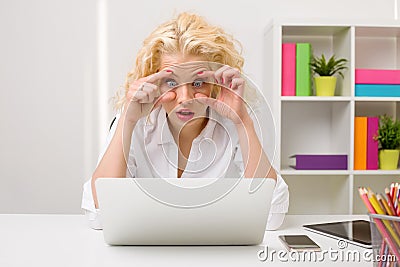 Woman in office looking at computer and holding her eyes open Stock Photo