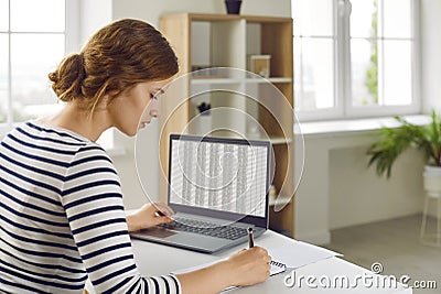 Woman office worker is working with spreadsheet on computers screens and making notes. Stock Photo