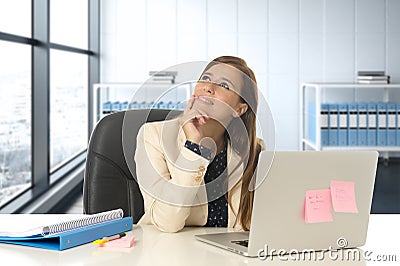 Woman at office working at laptop computer desk smiling happy thoughtful and pensive Stock Photo