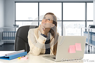 Woman at office working at laptop computer desk smiling happy thoughtful and pensive Stock Photo