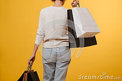 Woman in old loose comfortable jeans carrying bunch of shopping paper bags Stock Photo