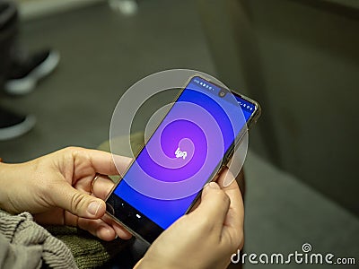 Woman opening Lyft mobile app with logo on Android screen while commuting on subway train Editorial Stock Photo