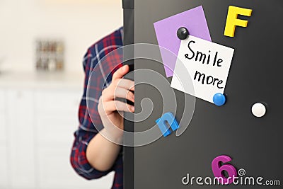 Woman opening refrigerator door with SMILE MORE note, closeup Stock Photo